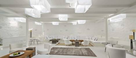 Un salón moderno y minimalista con muebles blancos, una mesa de madera y una alfombra grande.