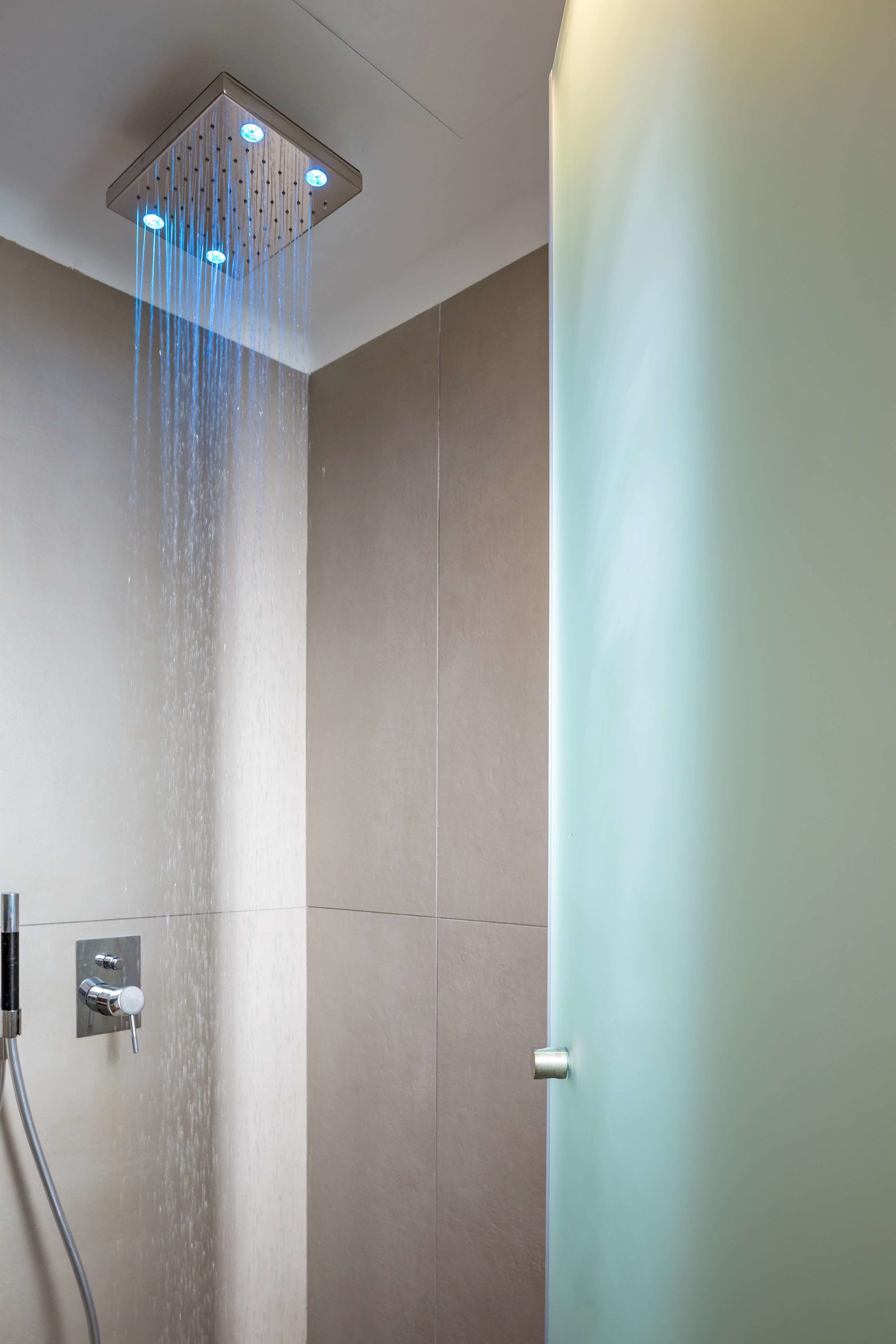 A modern shower with multiple nozzles and a control panel.