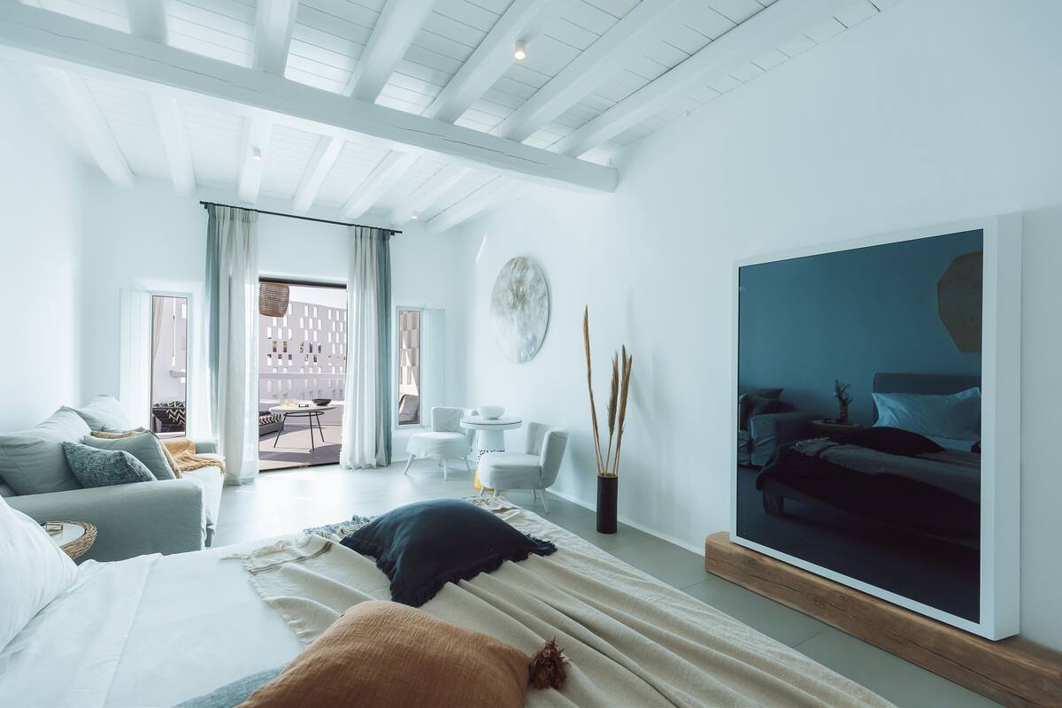 A modern bedroom with a large bed, a TV, and a view of a balcony.