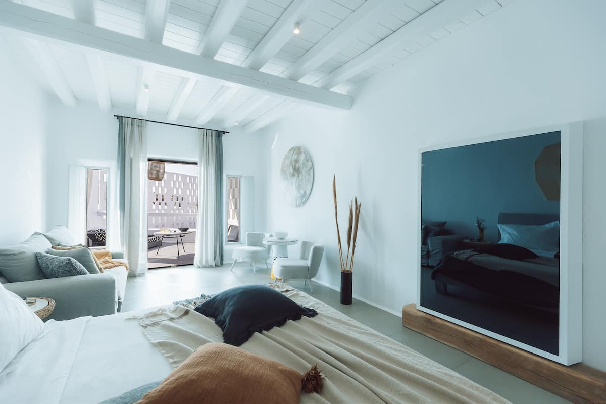 A modern bedroom with a large bed, a TV, and a view of a balcony.