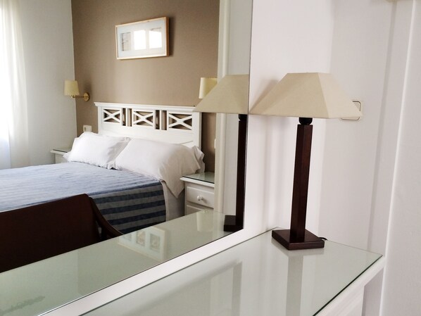 A hotel room with a bed, a bedside table, a lamp, and a framed picture on the wall. - Hotel Carbonell (Llanca)