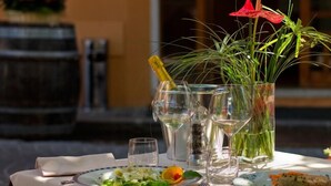A table set for two with plates of food, glasses, and a vase with green plants. - HOTEL DEPENDANCE SILVESTRO (Garda)
