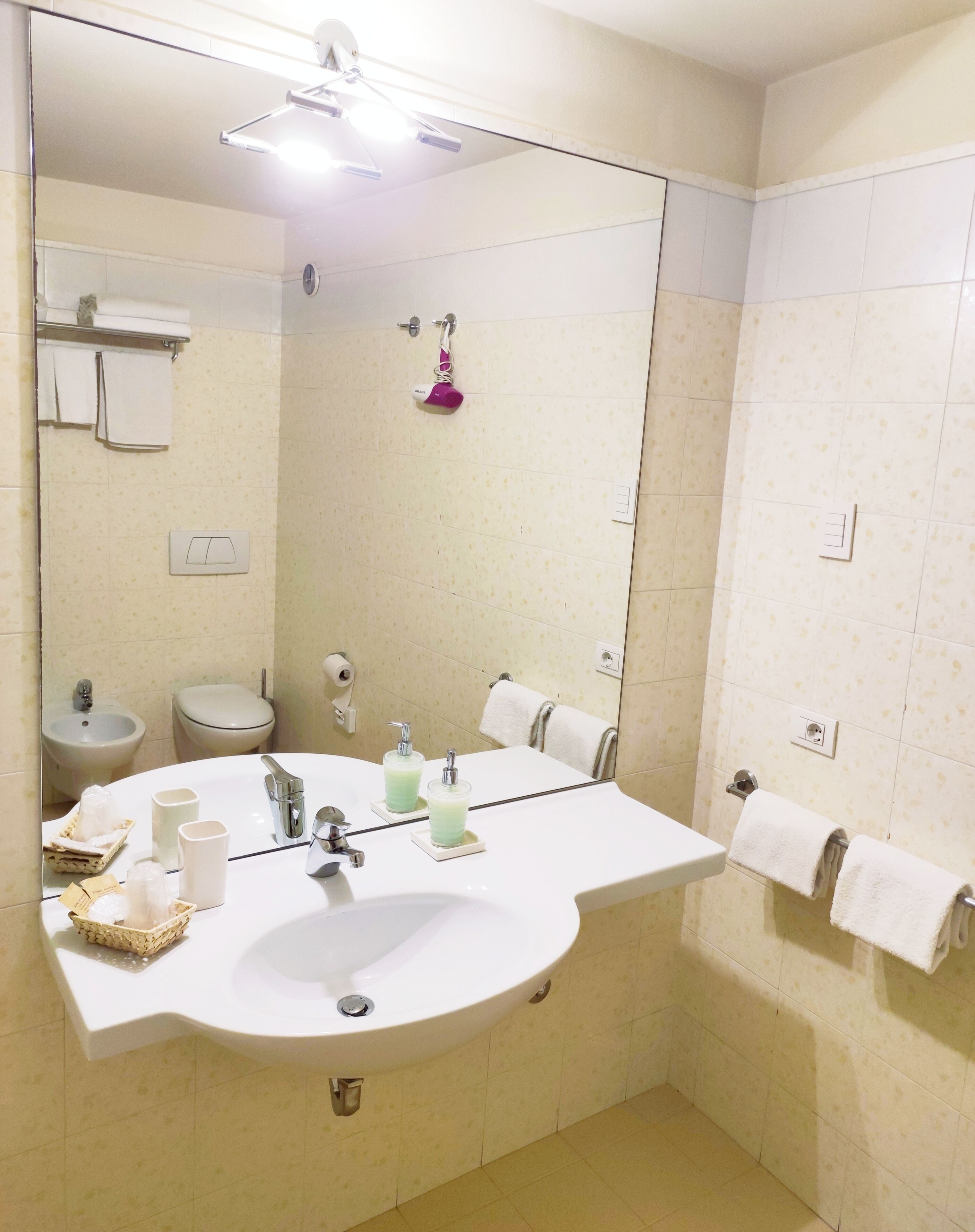 Un baño con un espejo grande, un lavamanos, un inodoro y una ducha.