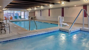 Una piscina interna con vista chiara sulla zona della piscina, comprensiva di una postazione per il bagnino, una scala di accesso e un’area con sedute.