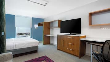 Une chambre d’hôtel moderne équipée d’un lit, d’un bureau, d’une télévision et d’une fenêtre donnant sur l’extérieur.