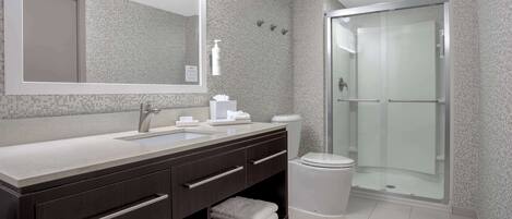 A modern bathroom with a large mirror, a sink, a toilet, and a glass-enclosed shower.