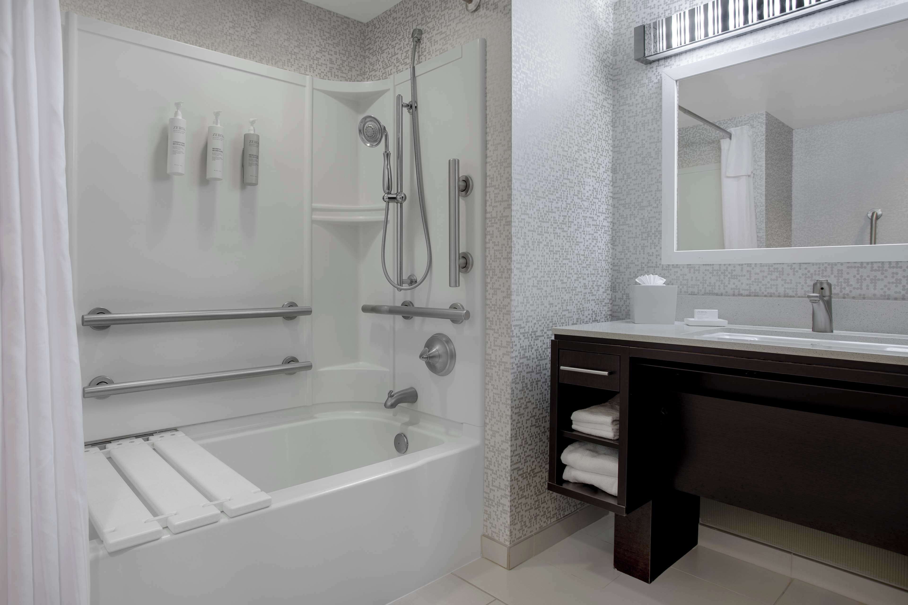 A modern bathroom with a glass-enclosed shower, a white bathtub, and a dark wooden vanity with a mirror.