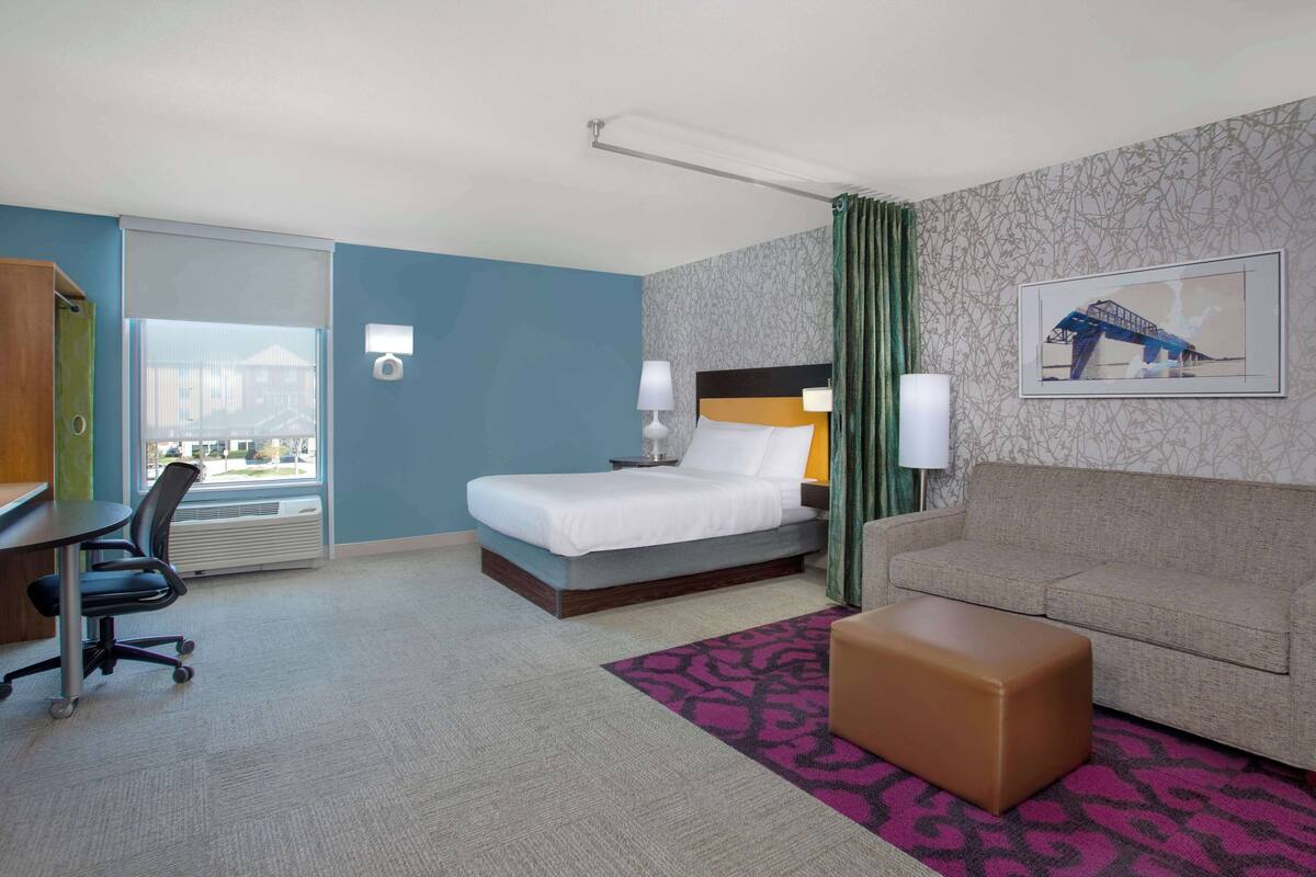 Una habitación de hotel con cama, sofá, escritorio y una silla.