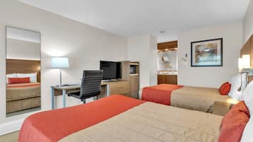 A hotel room with two beds, a desk with a computer, a television, and a mirror.