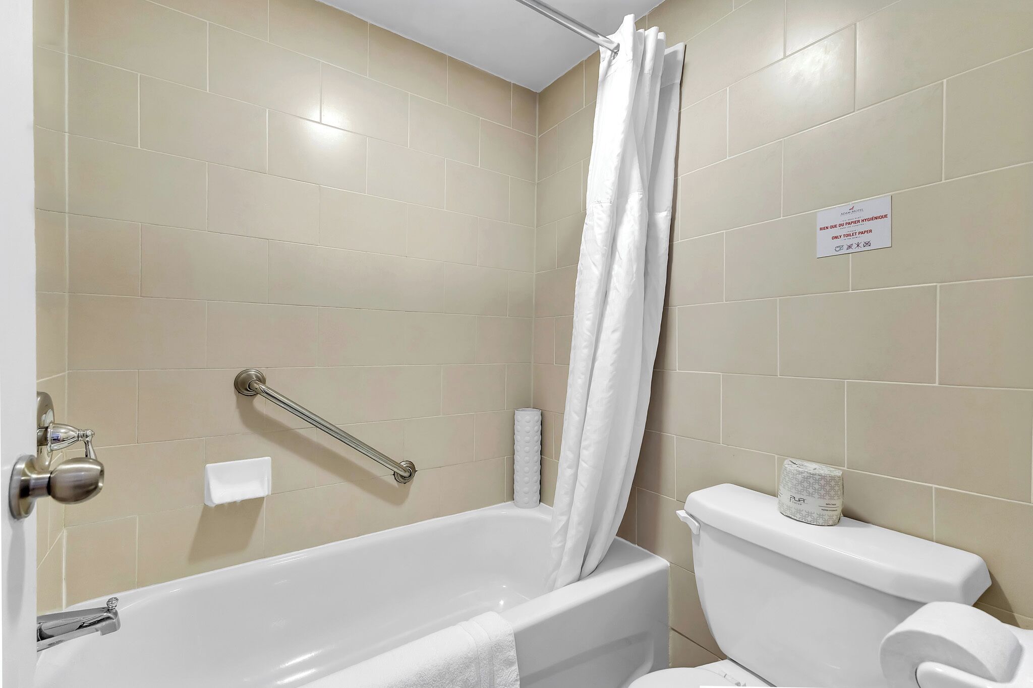 A bathroom with a bathtub, toilet, and a shower curtain.