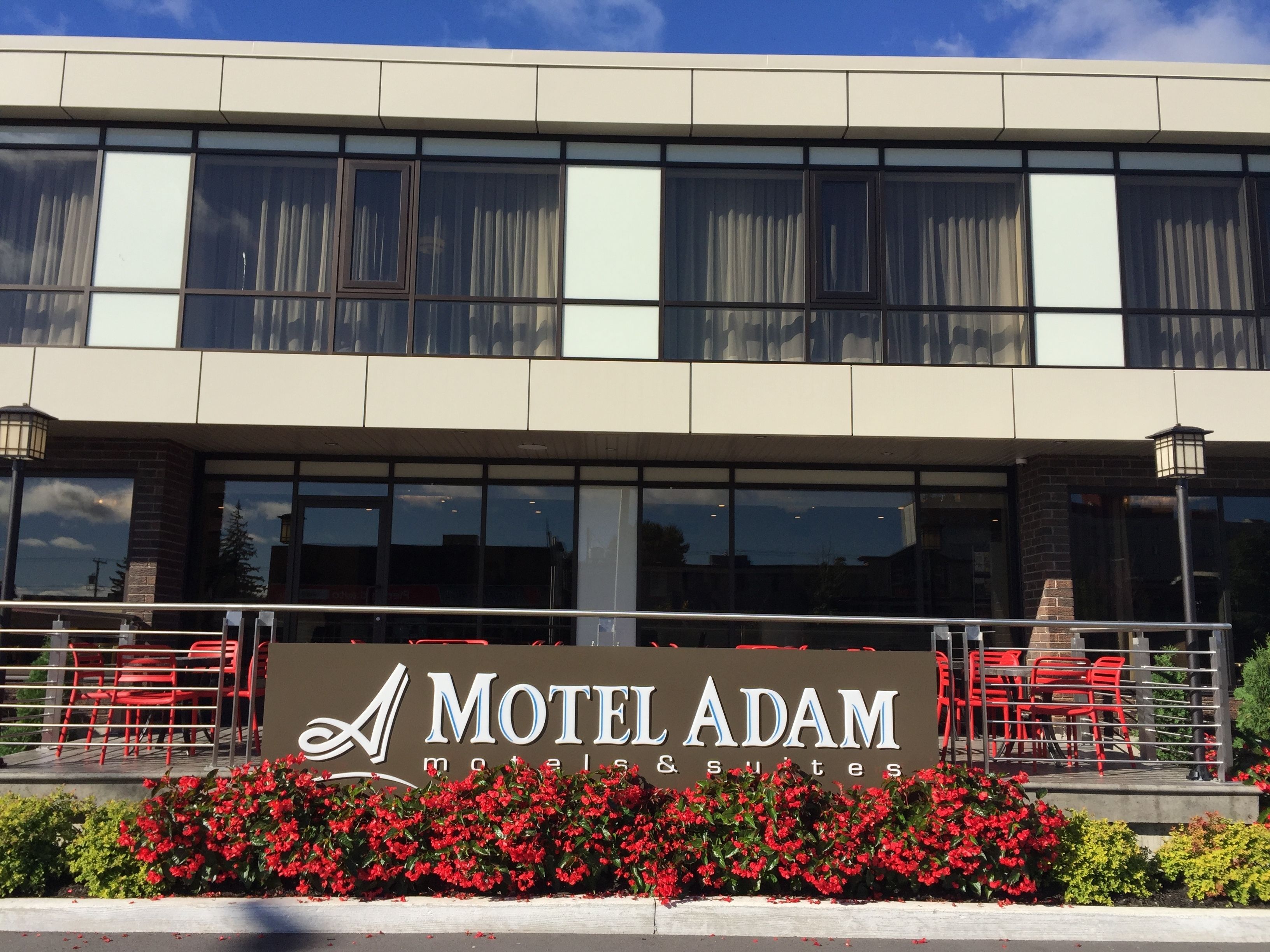 Um edifício com uma placa indicando Motel Adam, motéis e suítes.