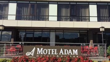 Um edifício com uma placa indicando Motel Adam, motéis e suítes.