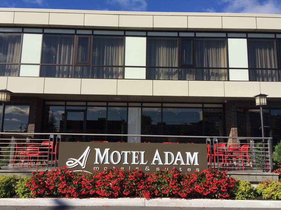 Um edifício com uma placa indicando Motel Adam, motéis e suítes.