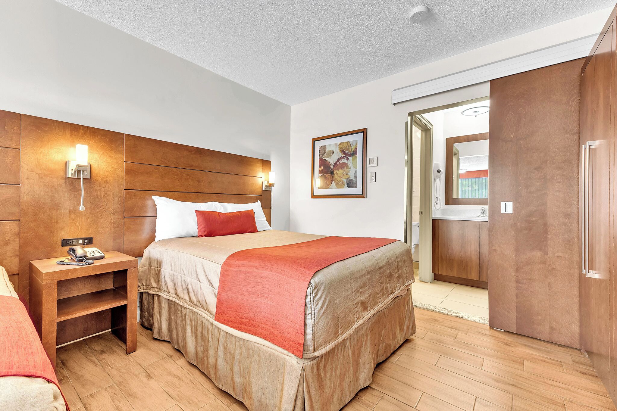 Une chambre d’hôtel comprenant un lit, une table de chevet, une lampe et une armoire.