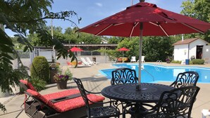 Un patio exterior con piscina, sillas de descanso y una mesa con sillas.