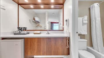 A modern bathroom with a wooden vanity, a Danby refrigerator, a shower curtain, and a toilet.