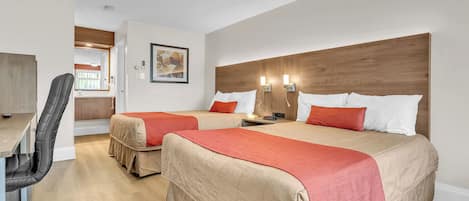 A hotel room with two beds, a desk, and a chair.