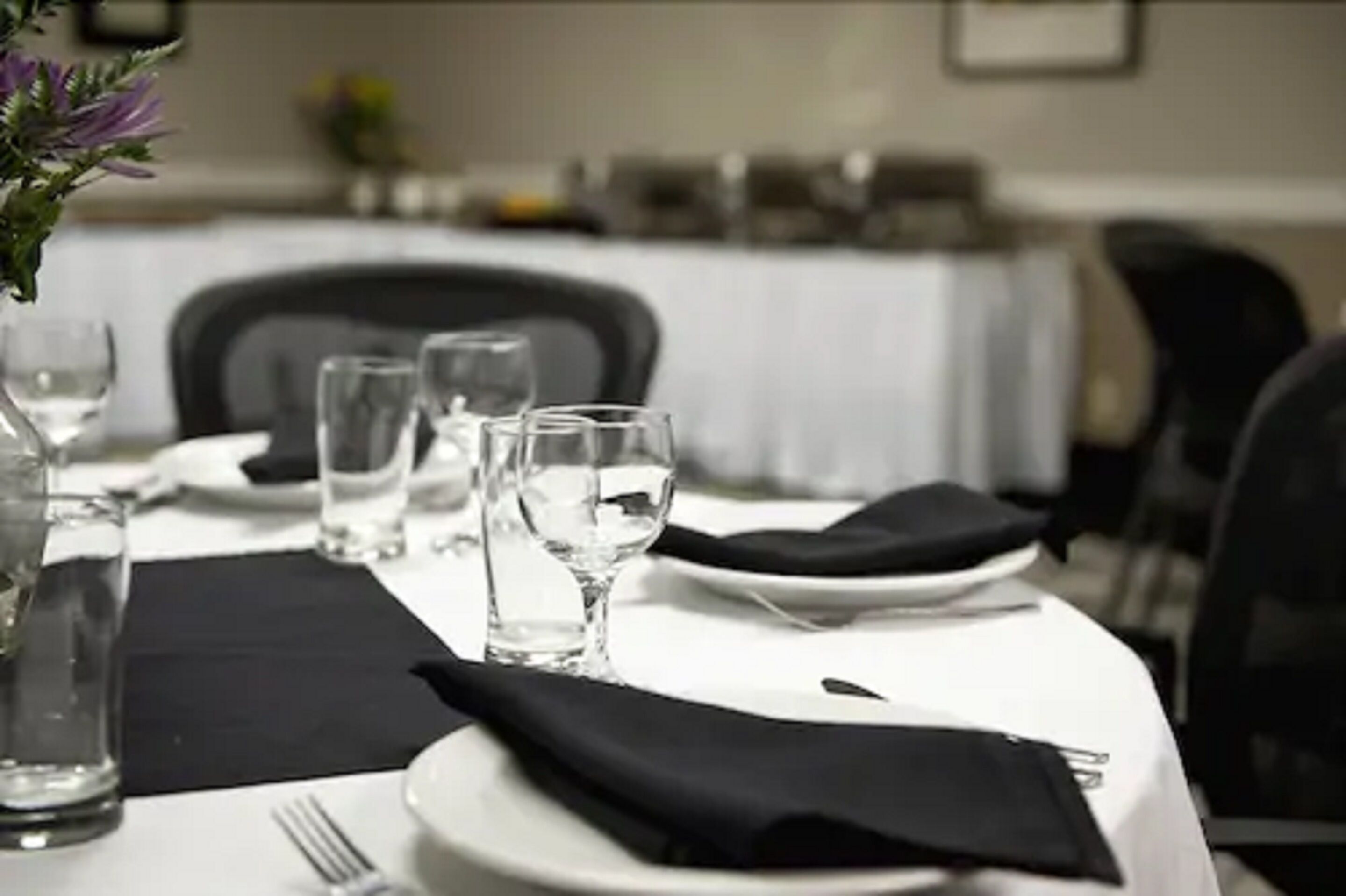 Una mesa de comedor dispuesta con platos, vasos y una servilleta.