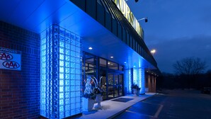 A building with a glass facade and a sign indicating it is approved by AAA. - Visitors Inn (Hamilton)