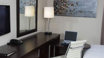 Une chambre d’hôtel équipée d’un bureau, de deux lampes, d’un ordinateur portable, d’une chaise et d’un lit.