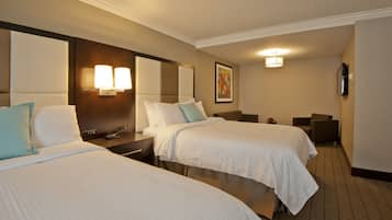 Ein Hotelzimmer mit zwei Betten, einem Nachttisch, einem Schreibtisch, einem Stuhl und einem Fernseher.