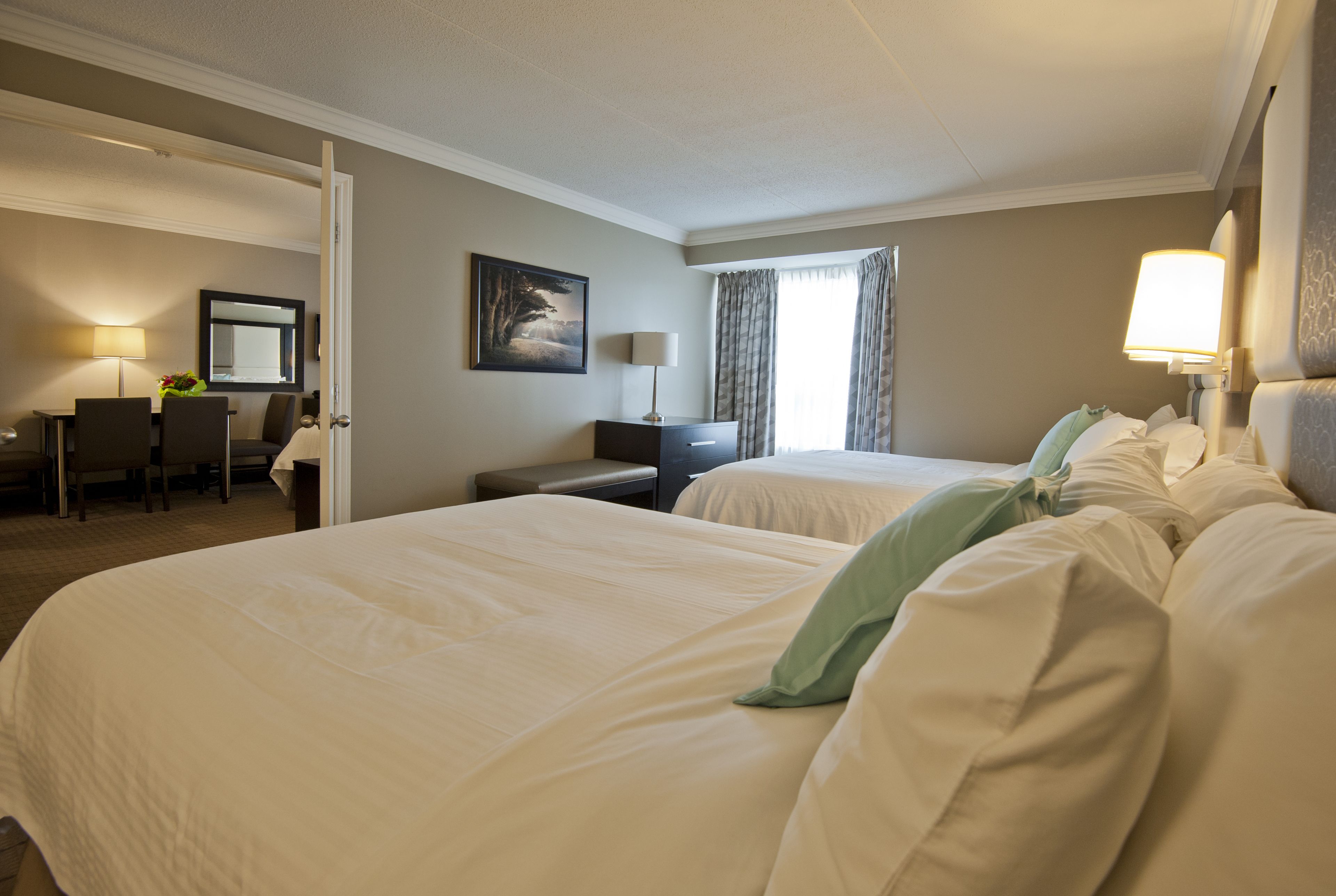 A hotel room with two beds, a desk, and a chair.