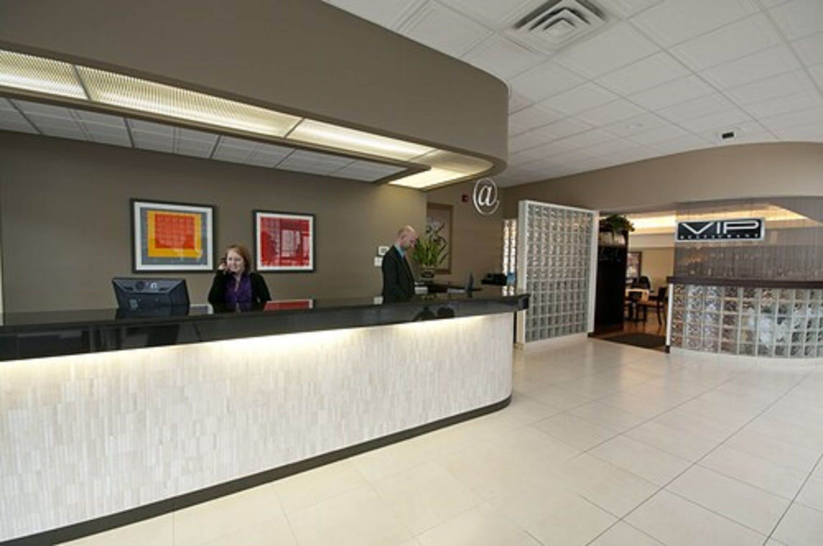 A reception area with a curved counter, framed artwork on the wall, and a sign with a logo.