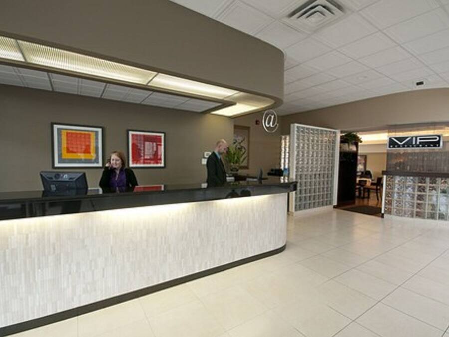 A reception area with a curved counter, framed artwork on the wall, and a sign with a logo.