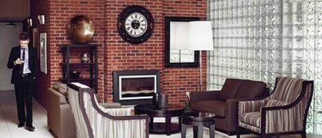Una sala de estar con pared de ladrillo, chimenea, reloj y ventana con diseño.