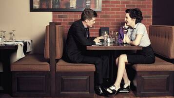 Un homme et une femme sont assis à une table dans un restaurant, avec un mur de briques en arrière-plan.