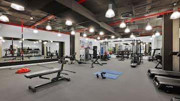 Una palestra con diverse attrezzature per esercizi, specchi e illuminazione con accenti rossi.