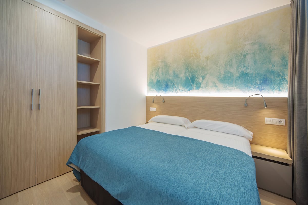 Un dormitorio moderno con cama, armario y apliques de pared.
