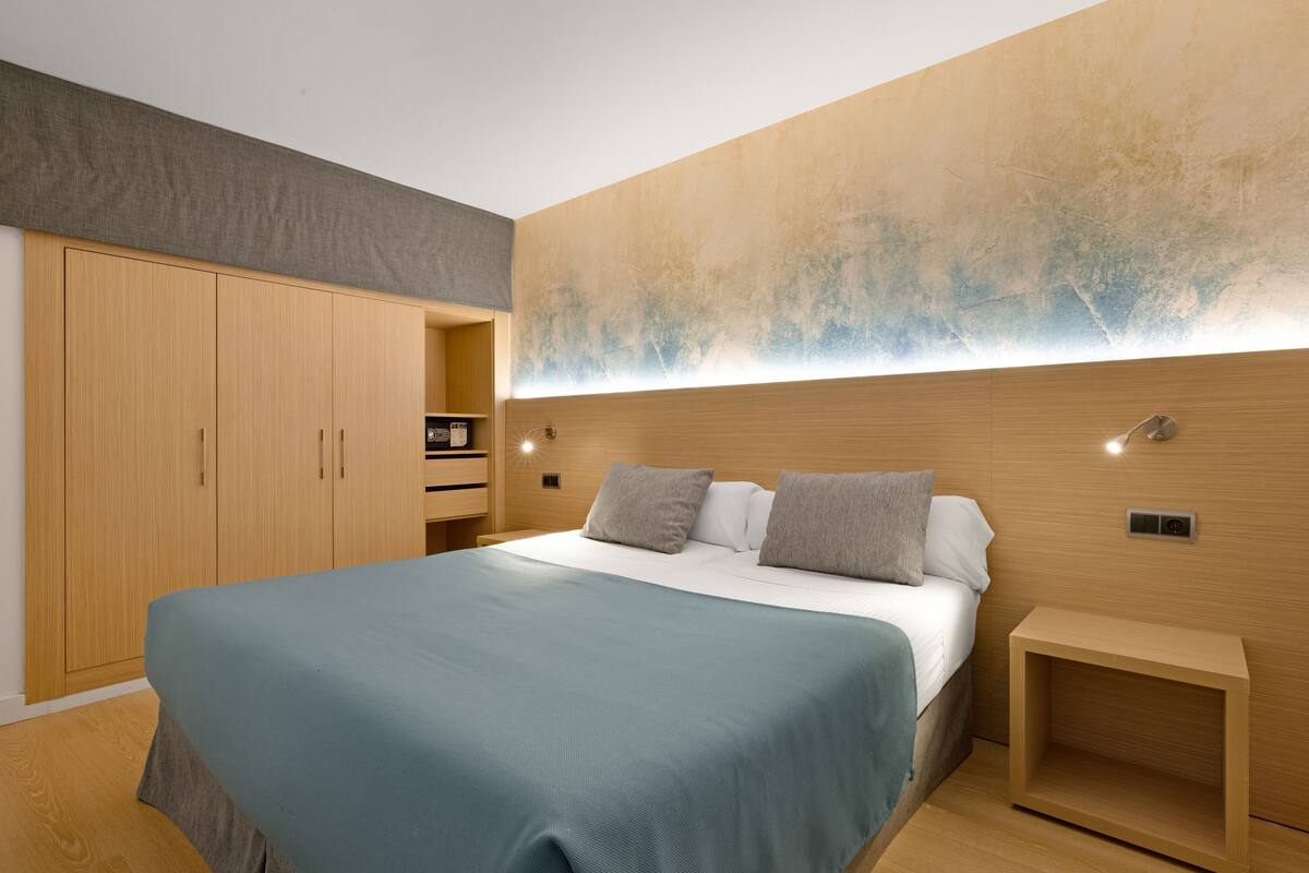 Un dormitorio moderno con una cama grande, un armario de madera y una mesita de noche.