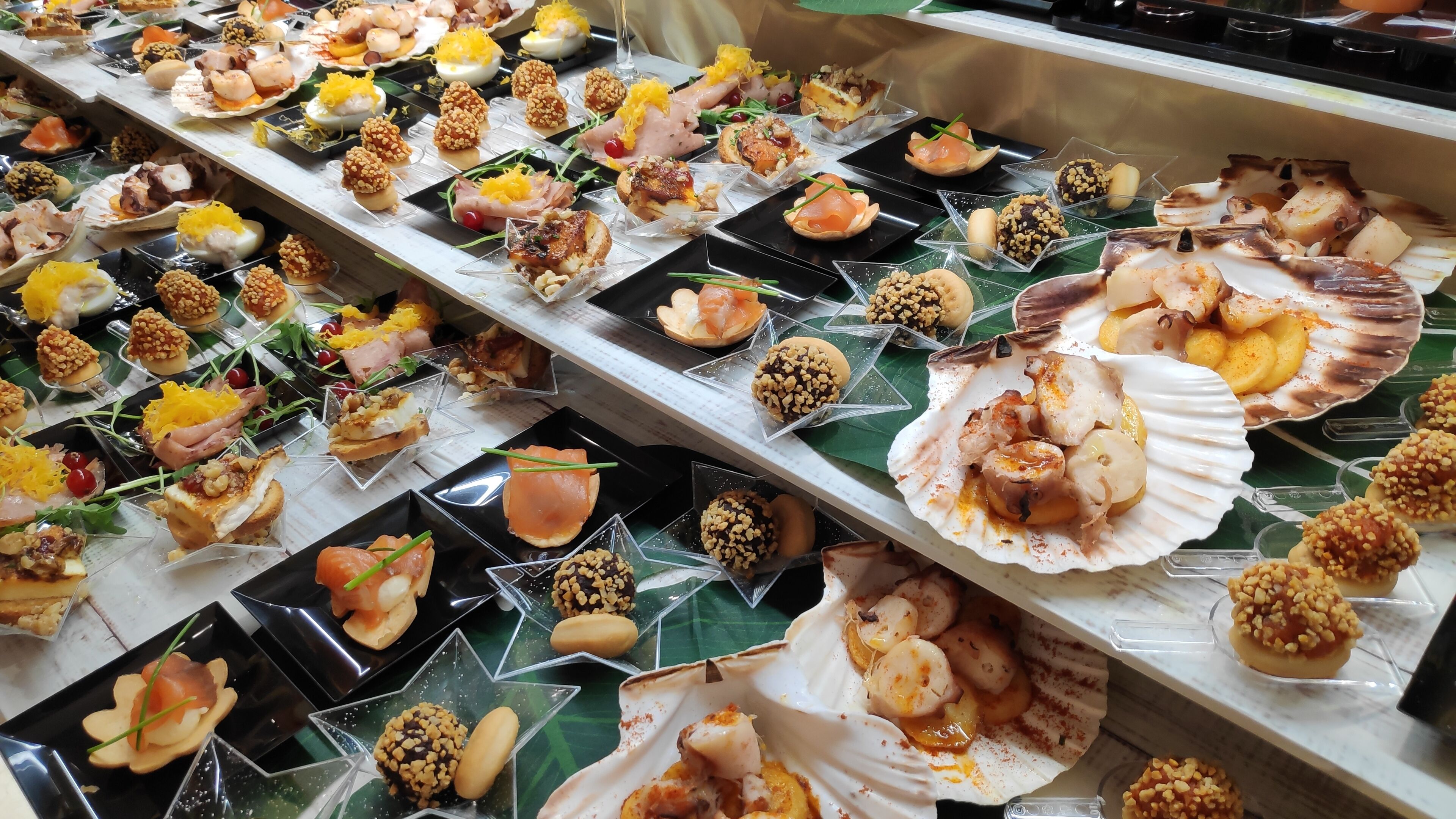 A buffet with various dishes arranged on plates and in clear containers.