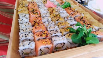 Een houten dienblad met verschillende sushirollen, waaronder zalm en tonijn, versierd met sesamzaadjes en wasabi.