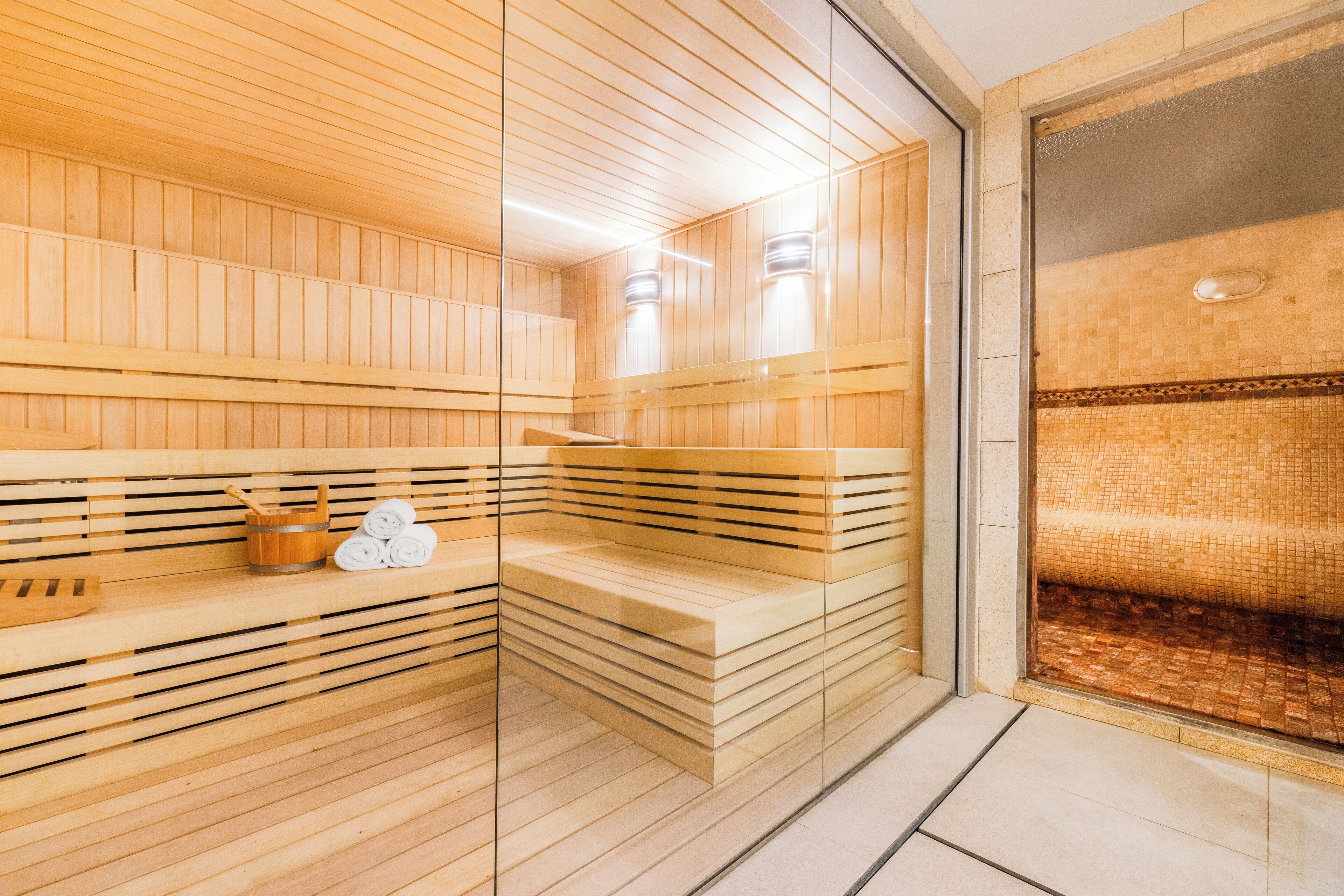 A sauna with wooden slats, a bench, and a glass door.