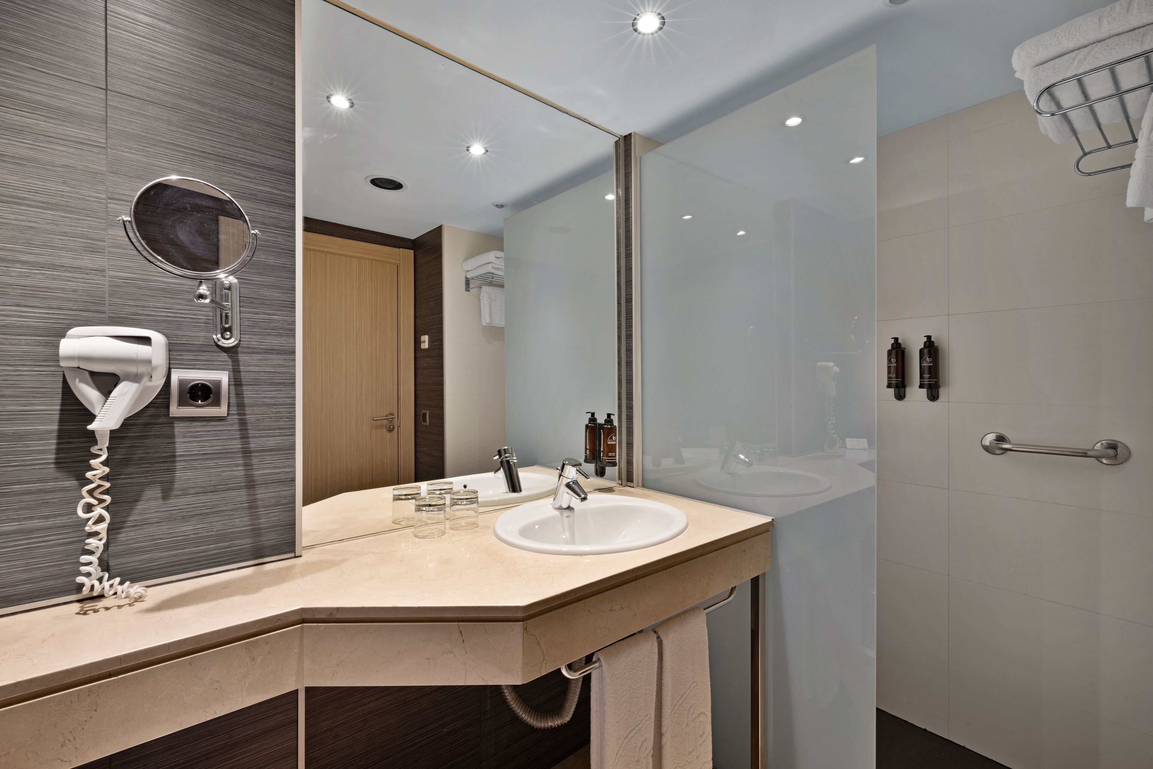 A modern bathroom with a large mirror, a sink, and a shower area.