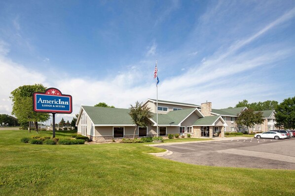 Een Amerikaans hotel met een groen dak, een vlaggenmast met de Amerikaanse vlag en een parkeerplaats.