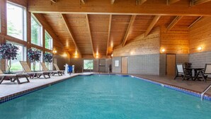 Una piscina con vigas de madera, paredes de azulejos y ventanas iluminadas por el sol.