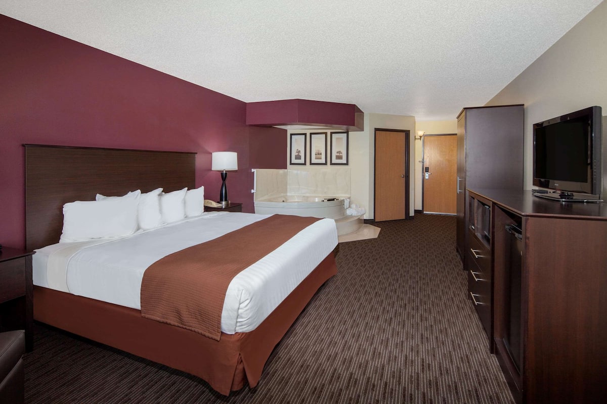 Ein Hotelzimmer mit einem großen Bett, einem Fernseher, einem Schreibtisch und einem Badezimmer.