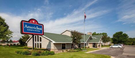 An American Inn with a green roof, a parking lot, and a flagpole with the American flag.