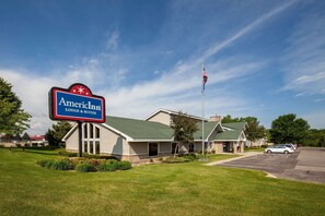 Een Amerikaans hotel met een groen dak, een parkeerplaats en een vlaggenmast met de Amerikaanse vlag.