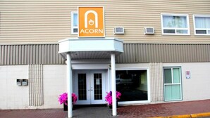 Un bâtiment avec une enseigne indiquant « ACORN » au-dessus de l’entrée, un espace d’entrée abrité et un panneau de signalisation pour le stationnement sur la droite.