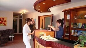 Un área de recepción con un mostrador de madera, un sofá y una estantería con libros y objetos decorativos.