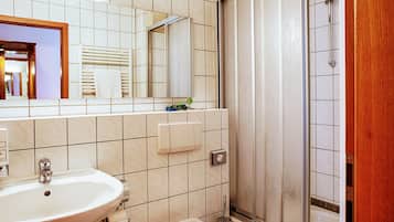 A bathroom with a sink, mirror, and shower.