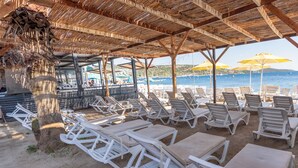 A beachside lounge area with white lounge chairs and tables, a thatched roof, and a view of the sea. - Bitez Garden Life Hotel - All Inclusive (Bodrum)