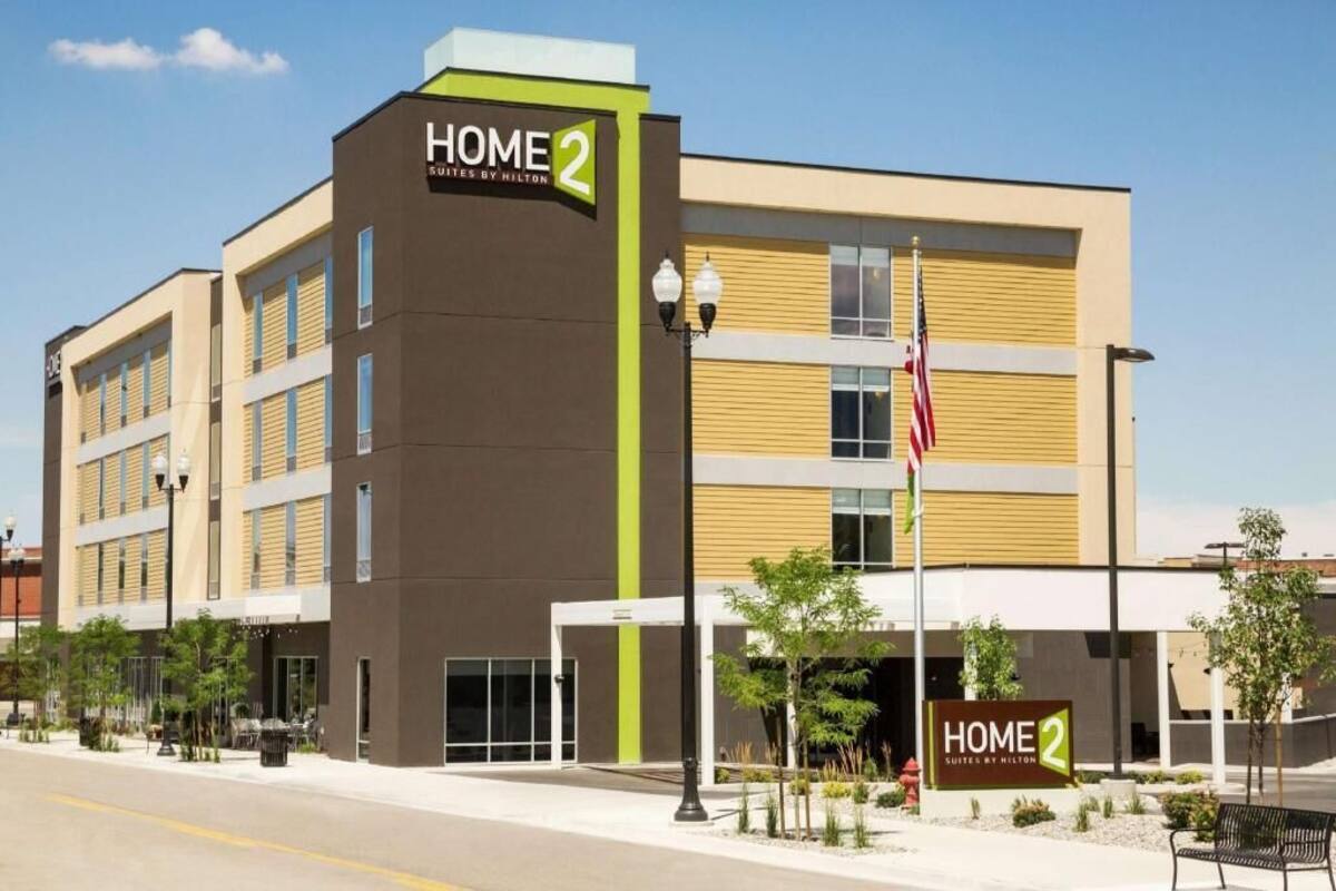 A modern hotel building with a sign reading 'HOME 2 SUITES BY HILTON.'