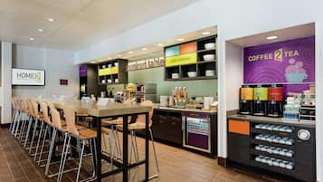 Comedor de hotel con una larga mesa, sillas, estación de café y un letrero que dice 'Inspired Table'.
