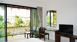 A hotel room with a balcony, a bed, a desk, a chair, and a TV. - The Nidhra (Ko Pha-ngan)