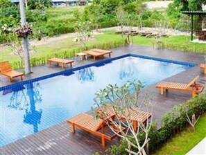 Una piscina al aire libre, sillones reclinables de piscina